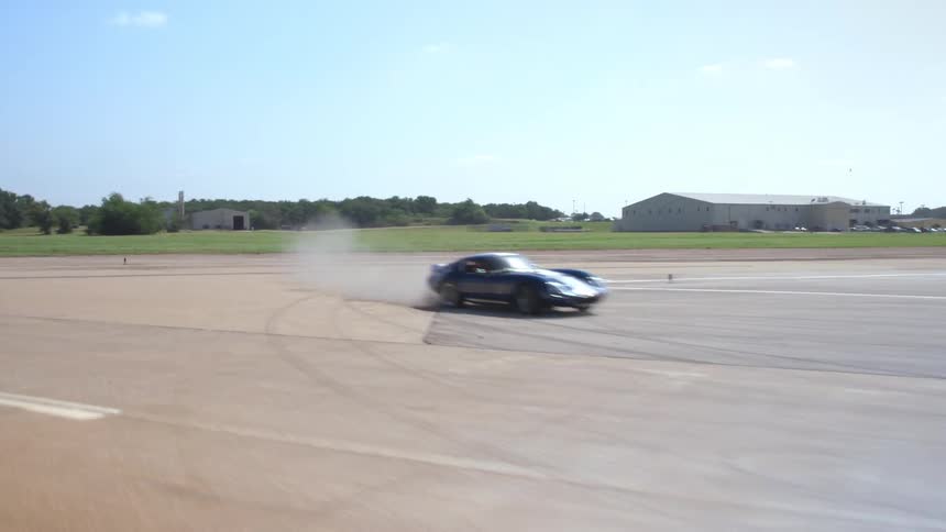 Racing car drifts through the wide turn on a racing track