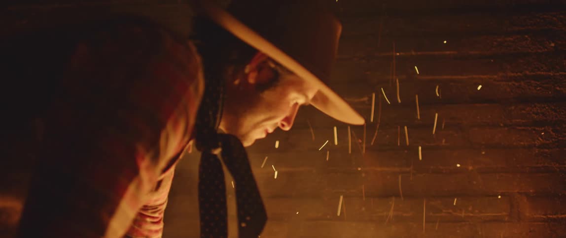 Man tends fire making embers spark and float up