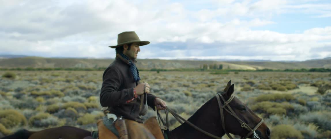 A man is riding a horse in a rural area during the day
