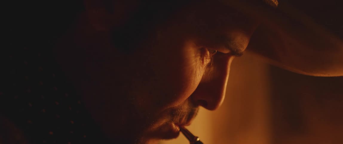 A man with a cowboy hat smoking on a pipe