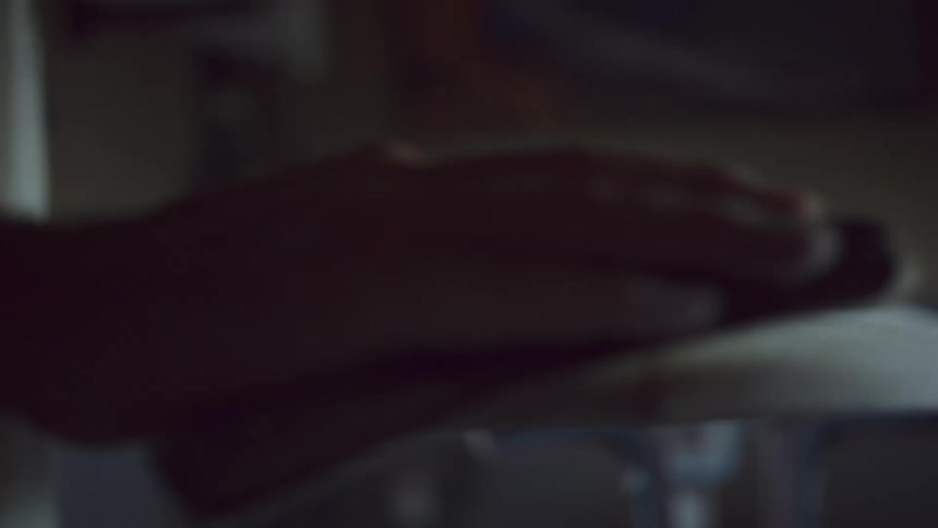 A man sands a surf board sitting on a stand indoors