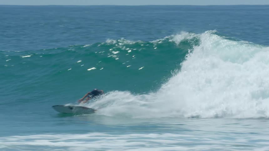 A surfer riding a large ocean wave on a beach
