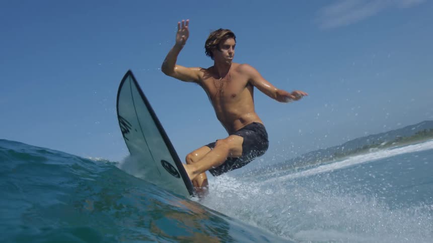 A young man surfing atop a wave quickly cuts back to change directions