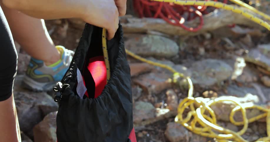 A person quickly threads a rope into a bag to stow it