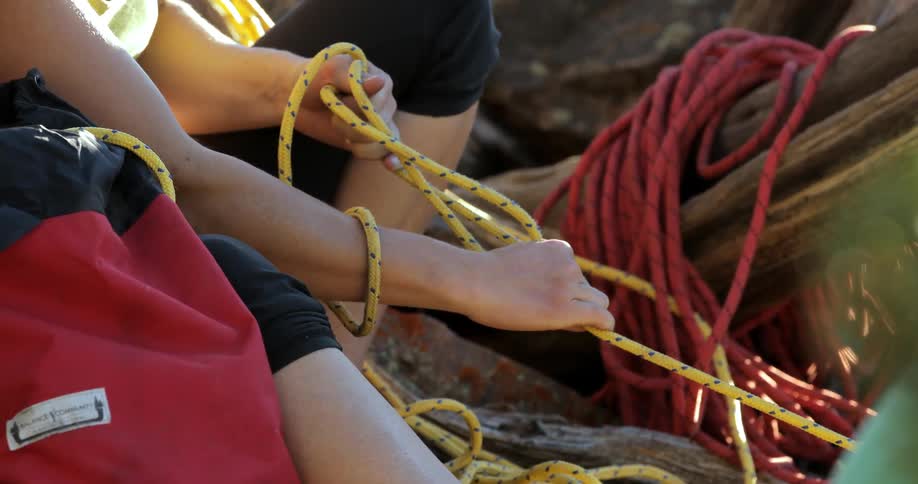 A person is holding a yellow rope tight in her arms