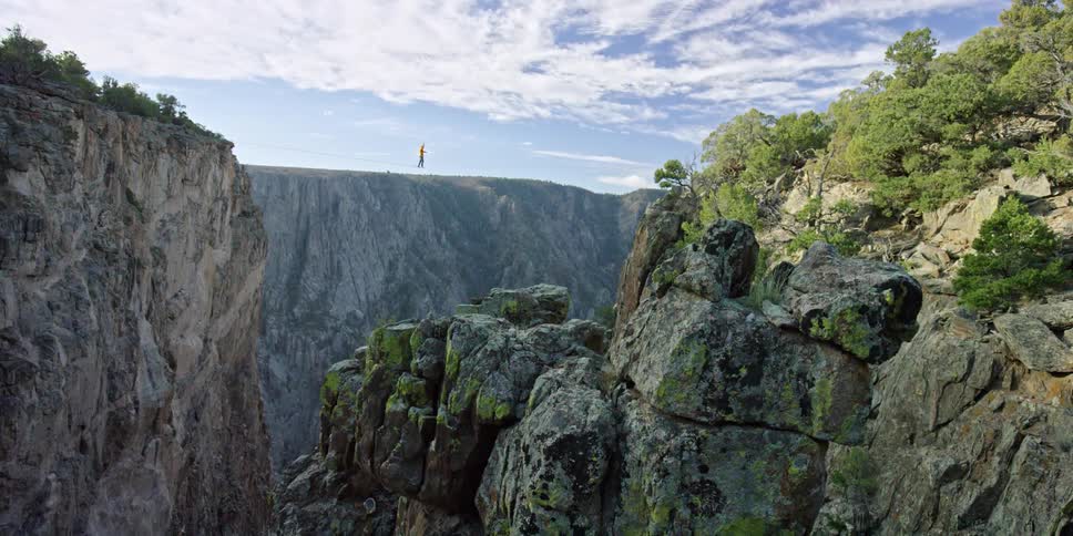 Person walking on a tightrope over a steep canyon
