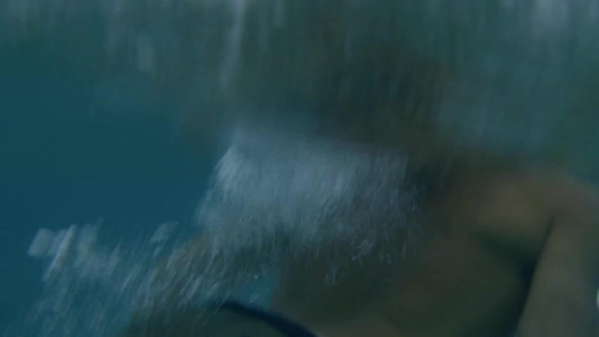 Young athletic man rides a surfboard on the blue clear ocean waters at sunset