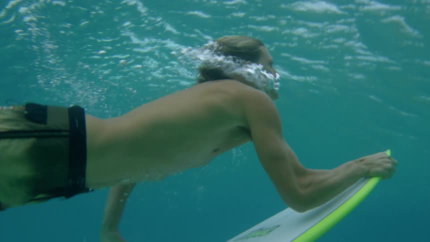 Surfer diving underwater then coming back up with surfboard