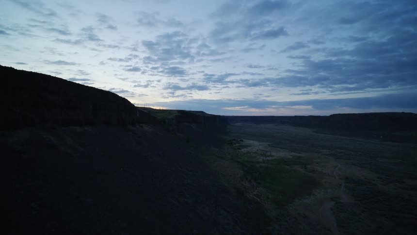 Rounding the bend of a canyon cliff to reveal farmland and crops growing near the edge