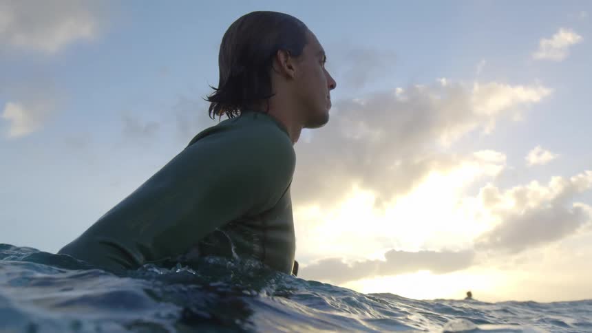 A man in the ocean turns and talks to another man