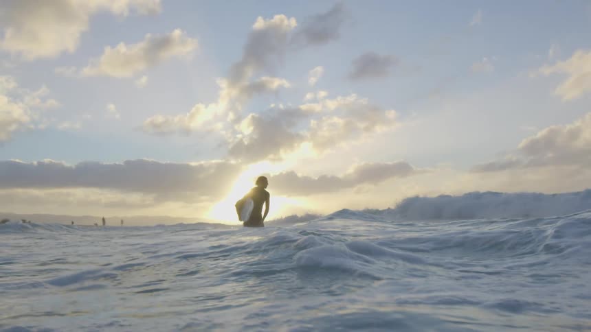 A guy is surfing in the ocean at dusk