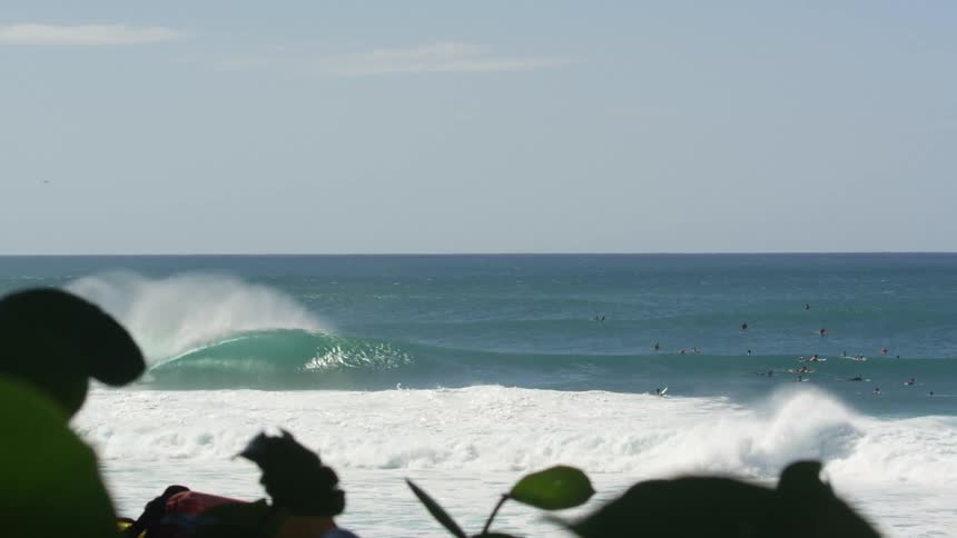 People brave past strong wind waves to swim and wade in the ocean
