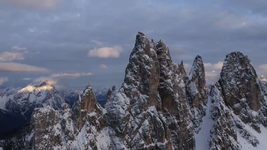 Sunlight peeks through clouds over a snow covered mountain range