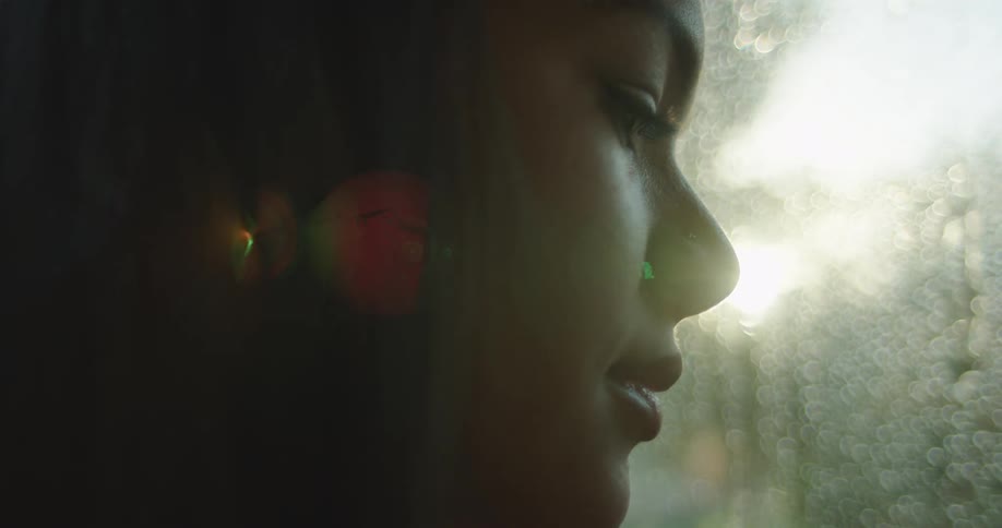 A woman is next to a window while its raining