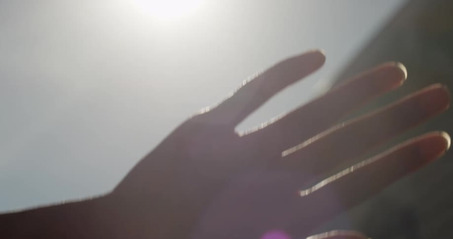 A hand blocking sunlight outside during the day
