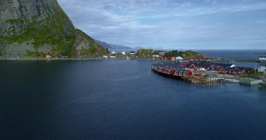 A view of the coast with a small town and red buildings with mountains and a blue sky