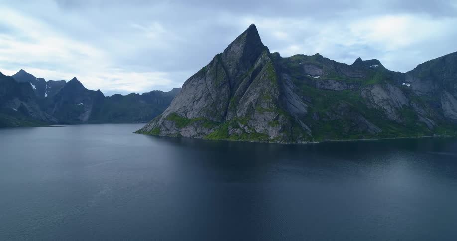 Water is calm in a fjord surrounded by tall cliffs in a canyon