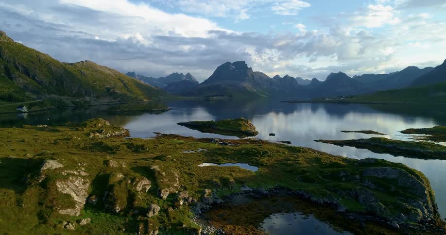An aerial view of a lake and mountains against a cloudy sky