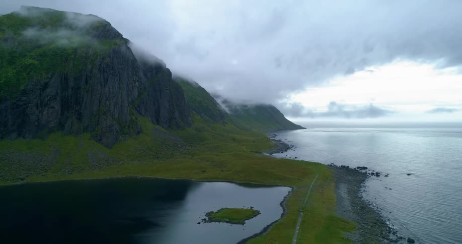 Cloud covered green mountain range on a coastal shoreline