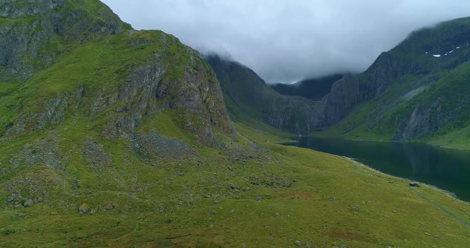 Aerial view of a river coming out of a canyon in the mountains under the clouds