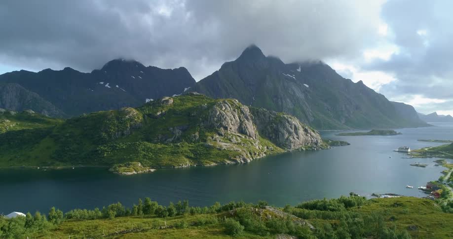 Clouds hang over mountain tops while a river flows nearby