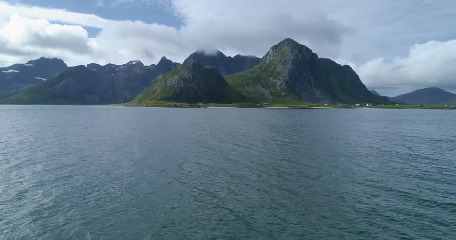 Mountains loom over the coast of a land mass on a bright day