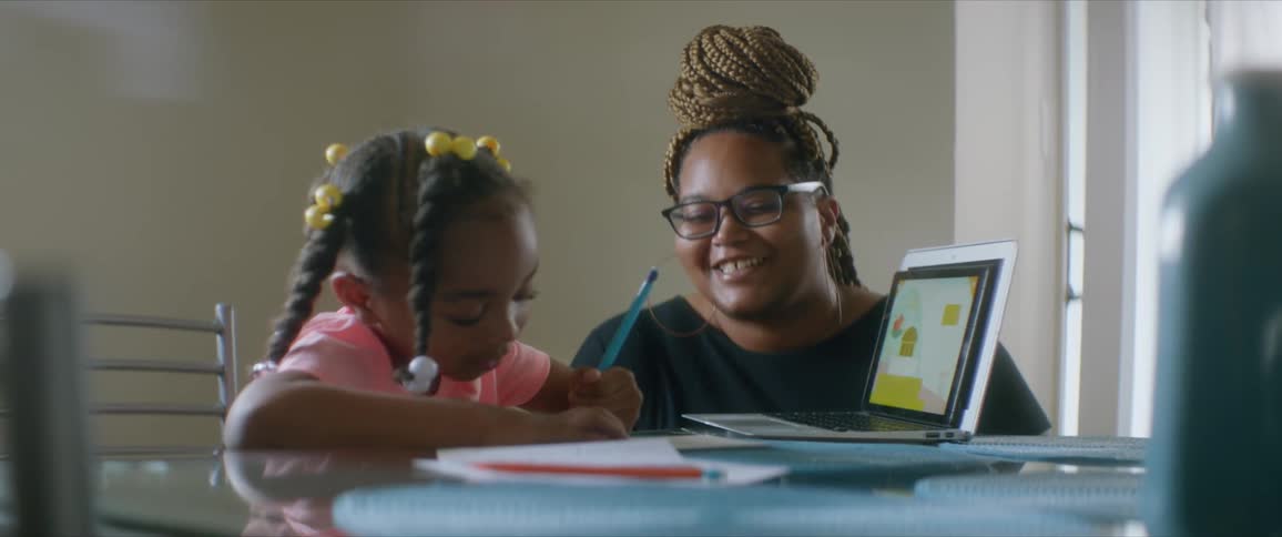 Mother helping daughter with homework sitting at a table at home