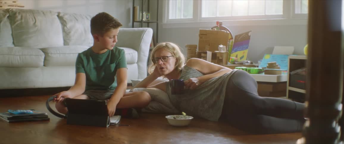 Mother and son on a living room floor while the sun studies on a computer