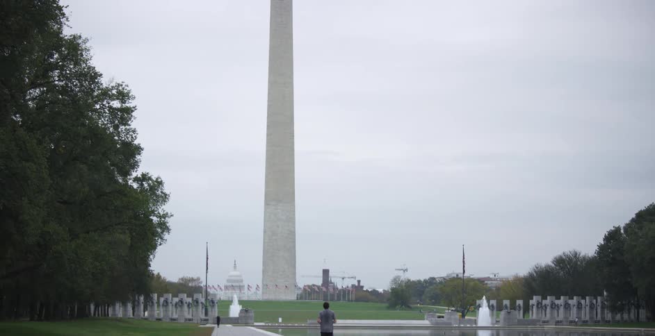 Young man jogging on the reflecting pool in front of the washington monument