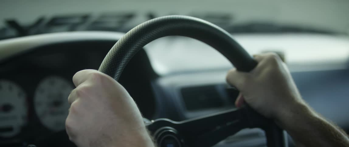 Driver of a race car grabs the steering wheel with determination