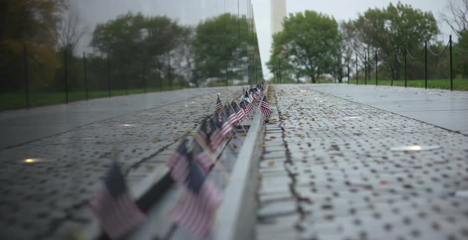 Several small american flags are placed in front of a memorial monument
