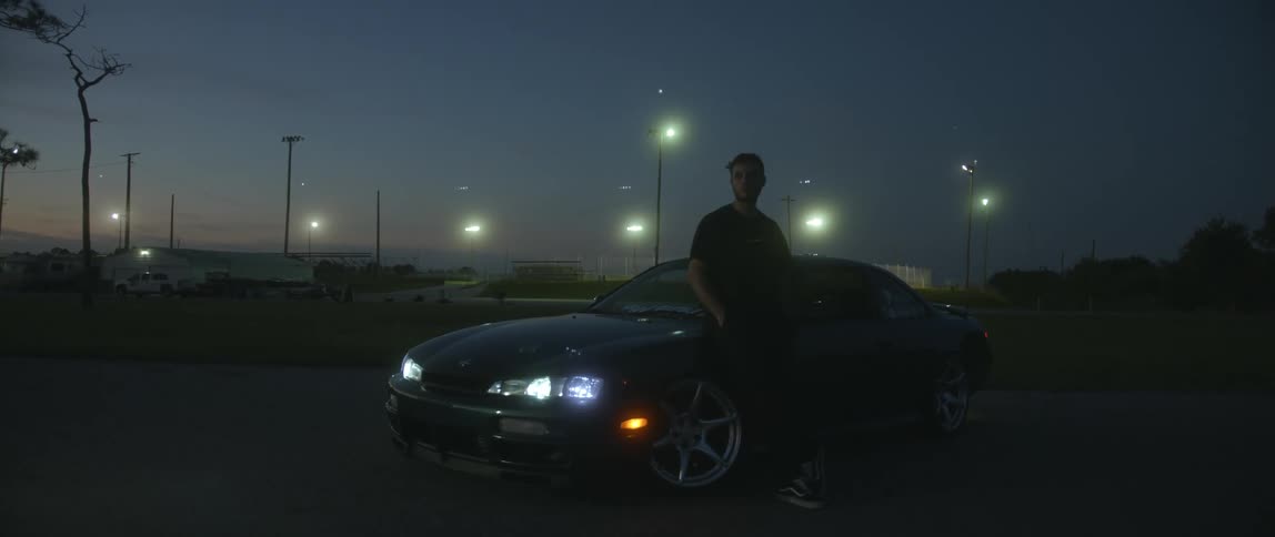 A man is standing by his car at night