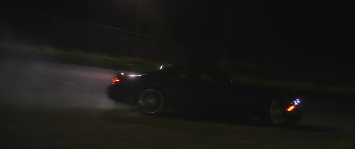 A car drives fast and drifts on a track at night