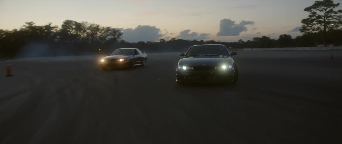 Two cars racing one another at dusk