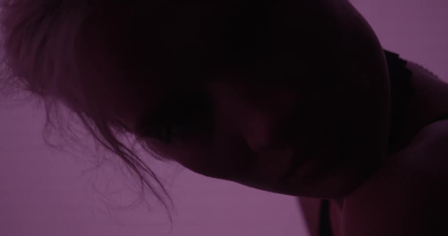 A model poses in front of a color changing digital screen and tilts her head to the side