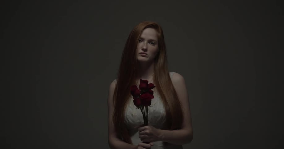 A woman holds a bunch of roses while looking at the camera