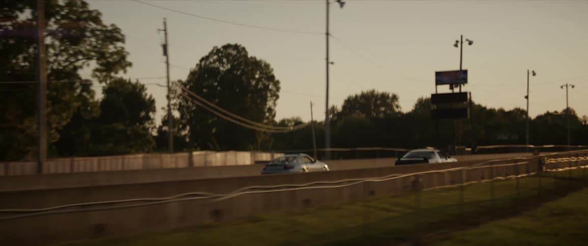 Two sports cars drive down a street next to one another