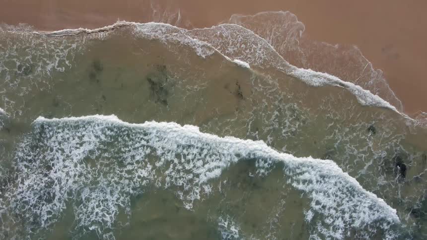 Waves roll over a sandy beach