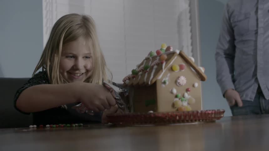 A girl is building a gingerbread house
