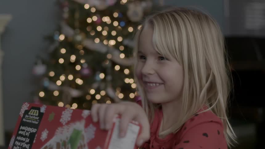 Little girl smiling while holding a present near a christmas tree