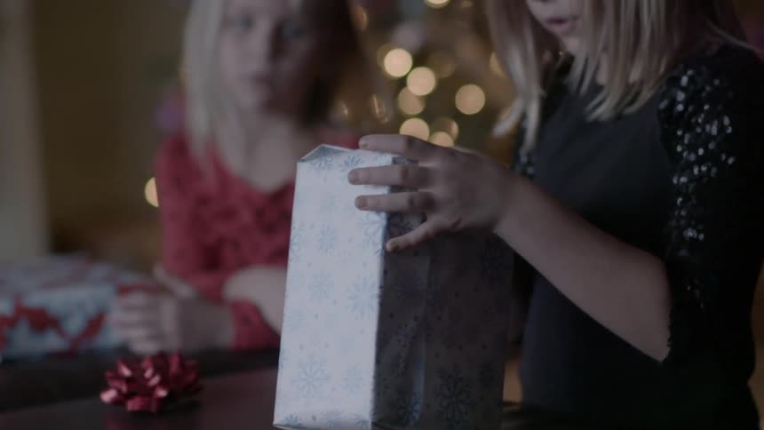 A blond girl opens a present