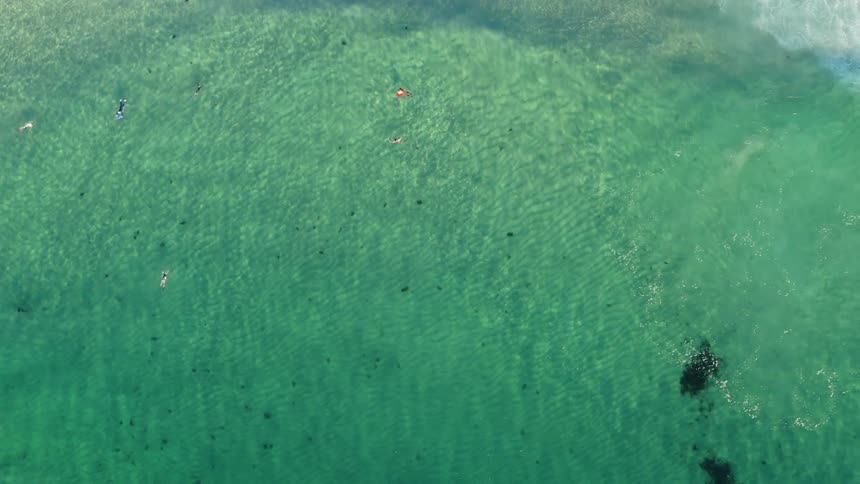 People lazily swim in clear ocean water