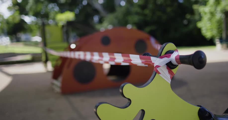 Caution tape is hund across yellow and orange playground structures outdoors in daylight