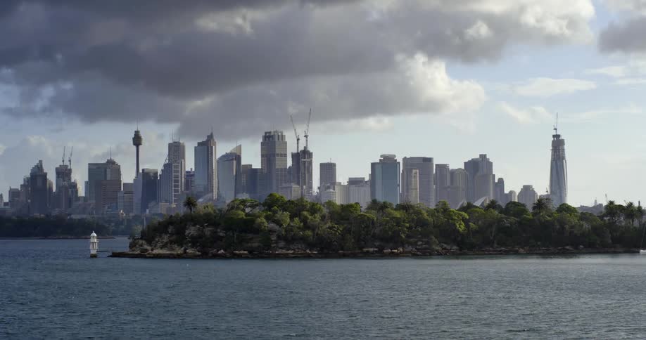 A city on a riverbank near an island of many trees