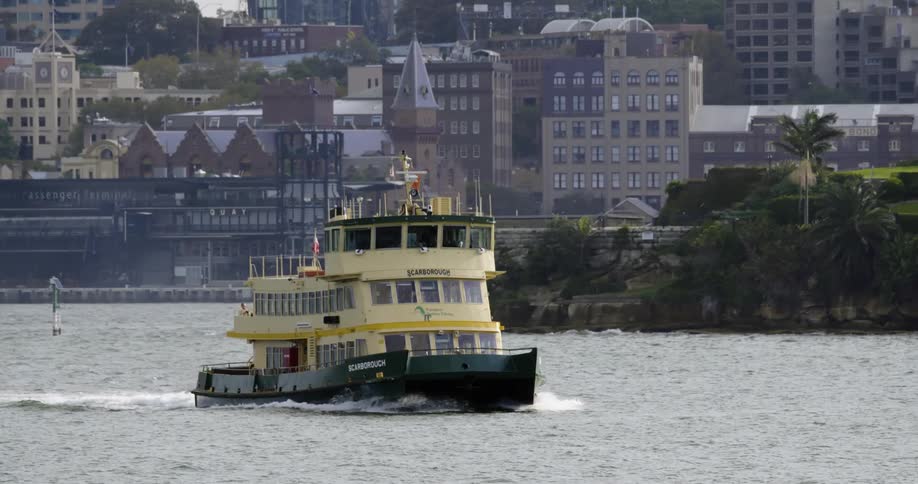A large boat travels along a waterway through a metropolis during the day