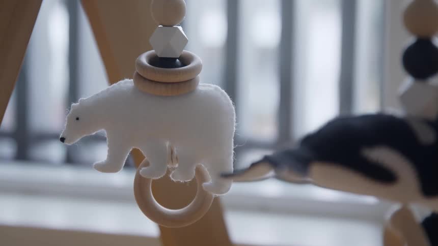 Polar bear plush toy hanging in a baby play gym inside a room