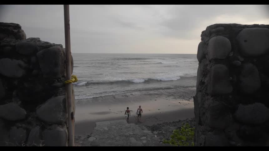 Two young surfers with surfboards walking towards the shoreline of a beach