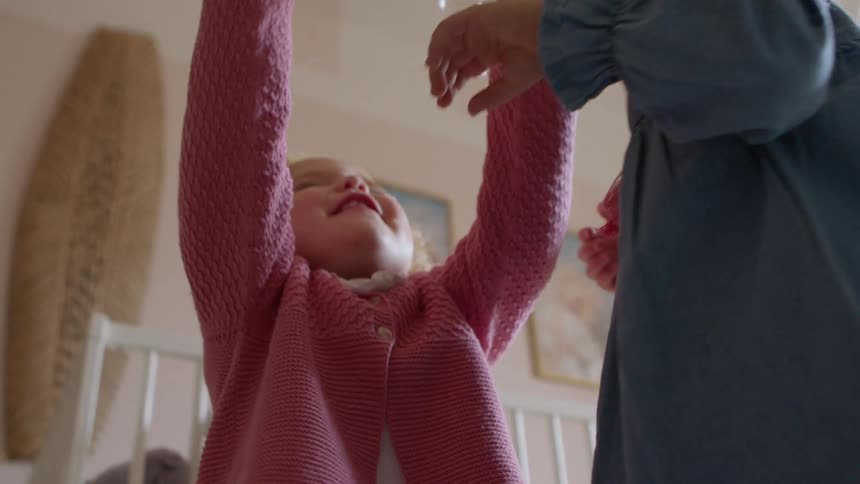 A pair of young girls laugh and play with bubbles falling from the air in a childs bedroom