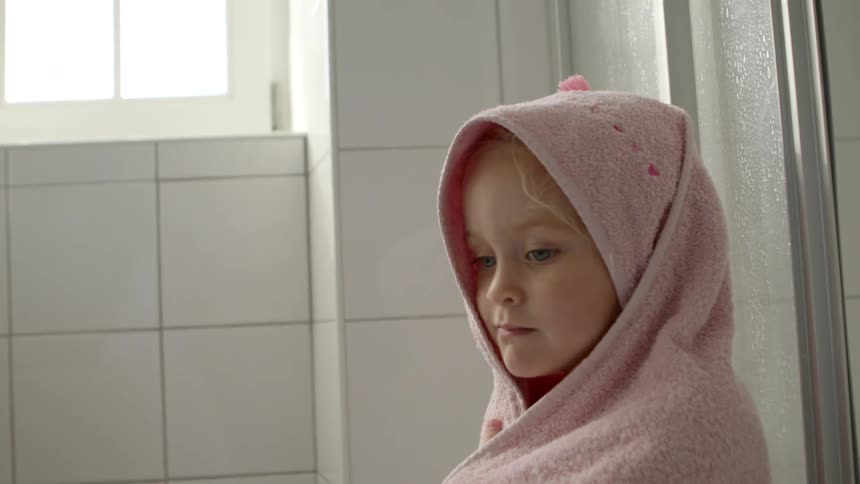 Children in a bathroom wrapped in towels with a wall and window in the background