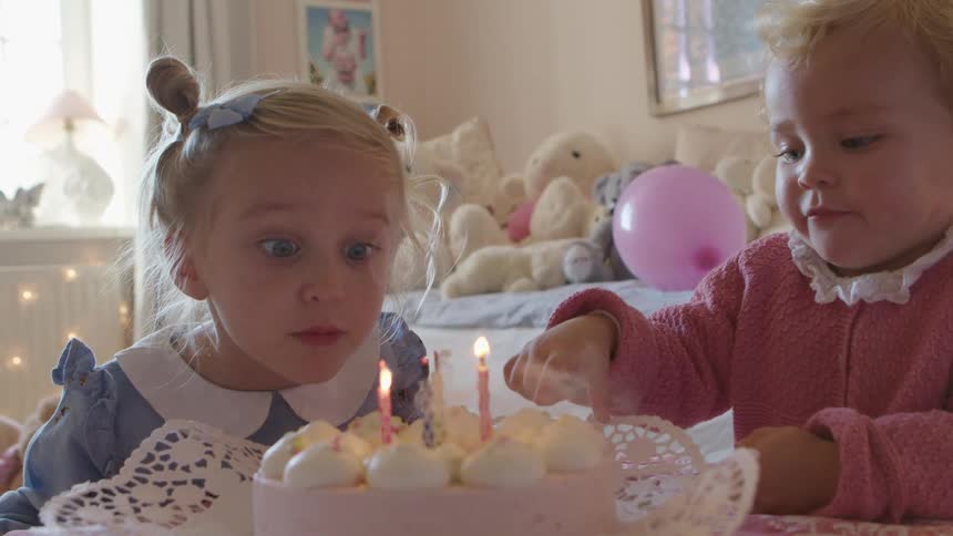 A girl in a room blows out candles in a birthday cake with fire and smoke